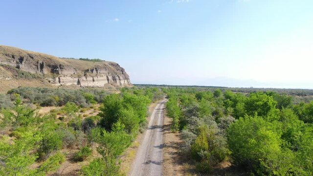 Aerial view road between trees.  Off road  near sand mine. Aerial footage road between field with dry grass and small trees. It's located near Sevan Lake, Armenia.