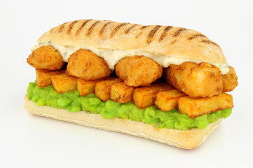 Fish and chips sandwich with battered cod fish and mushy peas in a panini bread roll