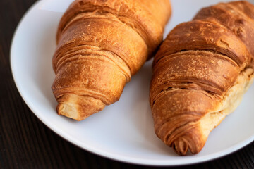 Fresh croissants on a white plate on a dark background