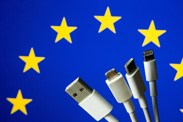 Concept for new EU legislation on USB-C universal charging cable. EUROPEAN UNION flag and different charging cables such as USB, USB-C, Micro USB, lightning cable.  - obrazy, fototapety, plakaty
