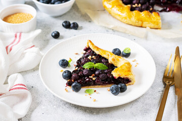 A piece of homemade galette with blueberries in a white plate on a culinary background close-up. Delicious sweet pastries	