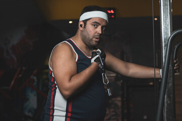 a funny fat boy doing sports inside a gym.
overcoming concept.
willpower.