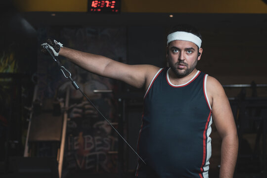 a funny fat boy doing sports inside a gym.
overcoming concept.
willpower.