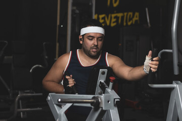 a funny fat boy doing sports inside a gym.
overcoming concept.
willpower.