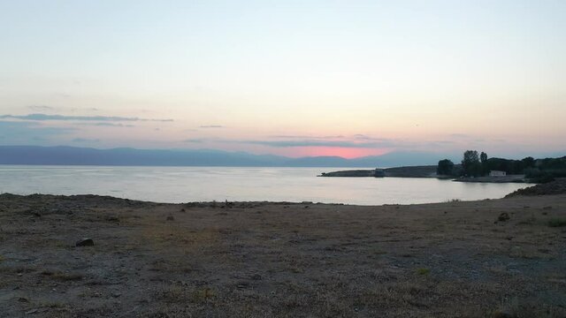  Aerial view lake in sunset. Aerial footage Sevan lake in Armenia. Drone slowly fly to water in lake in sunset time. Amazing view, Touristic place. 