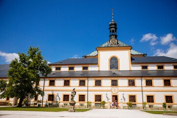 Fototapeta na wymiar Kuks, East Bohemia, Czech Republic, 10 July 2021: Baroque castle and hospital Kuks, courtyard with antique sundial on the facade, Beautiful complex with chateau and Holy Trinity Church at summer day.