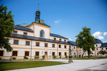 Kuks, East Bohemia, Czech Republic, 10 July 2021: Baroque castle and hospital Kuks, courtyard with antique sundial on the facade, Beautiful complex with chateau and Holy Trinity Church at summer day.