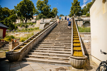 Kuks, East Bohemia, Czech Republic, 10 July 2021: well or a fountain with statues of Triton Greek god of sea, staircase with water cascade at sunny summer day, baroque castle and hospital Kuks.