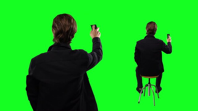 Changing Channels TV Remote Green Screen, Full And Close Up Shot Male. Man changing channels with a TV remote on a green screen background for replacement. Man standing and sitting