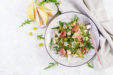 Salad of pear, blue cheese, grape, prosciutto, arugula and nuts with spicy dressing on a light...