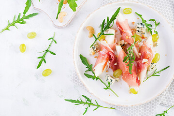 Appetizer with pear, blue cheese and prosciutto ham for holidays on a white plate. Top view, flat...