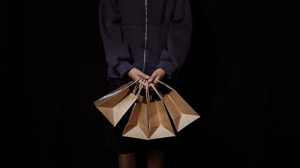 Set of paper shopping bags held by a person's hand on a black background