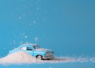 small toy blue car in the snow on a blue background, the concept of the new year minimalism