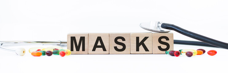 The word MASKS is made of wooden cubes on a white background with medical drugs