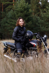 Fototapeta na wymiar woman on a motorbike in nature. biker motorcycle ride through the woods