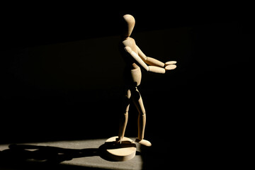 Wooden man taking a step into the dark towards the unknown in the future 