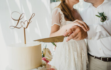 Crop newlyweds cutting wedding cake together