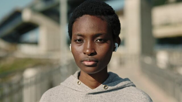 Portrait of african american woman standing on street in wireless earphones