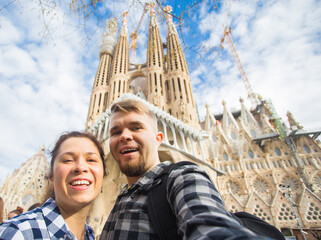 Happy tourists photographing in front of the famous Sagrada Familia roman catholic church in Barcelona, architect Antoni Gaudi