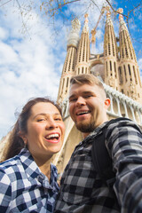 Happy couple making selfie photo in front of the famous Sagrada Familia catholic cathedral. Travel...
