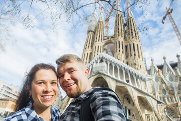 Happy tourists photographing in front of the famous Sagrada Familia roman catholic church in Barcelona, architect Antoni Gaudi