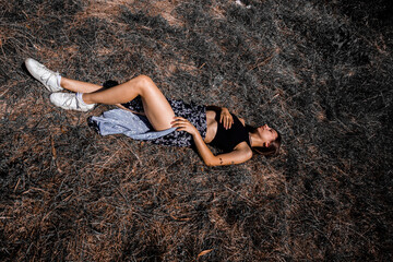 A beautiful young slender girl lies on dry grass and rests with closed eyes. Mysterious girl. High...