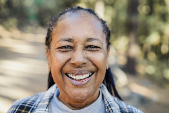 Senior african woman smiling on camera with forest in background - Focus on face