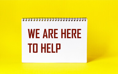 Simple conceptual design of customer service - close-up of notepad with text We are here to help on yellow background