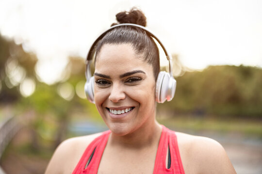 Portrait of curvy woman listening playlist music after jogging routine outdoors - Focus on face
