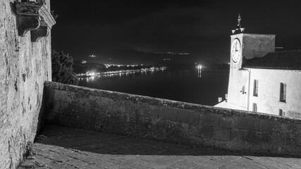 panoramic view to old wall and tower with clock in night shoot of italian city