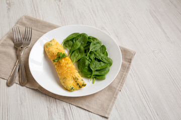 Homemade French Omelette with Fresh Herbs and Greens on a plate, side view. Copy space.