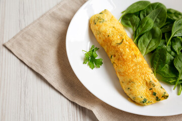 Homemade French Omelette with Fresh Herbs and Greens on a plate, side view. Space for text.