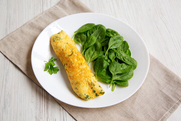 Homemade French Omelette with Fresh Herbs and Greens on a plate, side view.