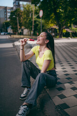 a beautiful girl is eating ice cream on the street in bright clothes and with bright modern makeup