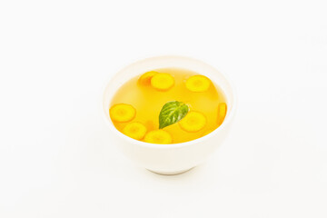 Transparent chicken broth with vegetables in ceramic bowls