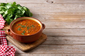 Red lentil soup in bowl on rustic wooden table. Copy space