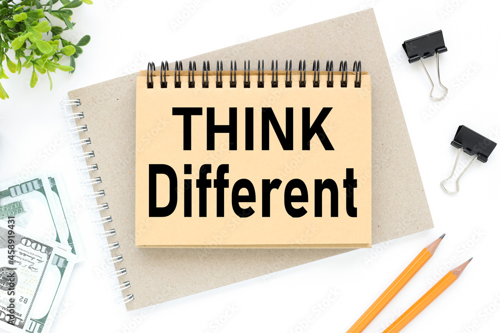 Poster word think different. table top view with notepad, pencils, bills and plant with copy space on white