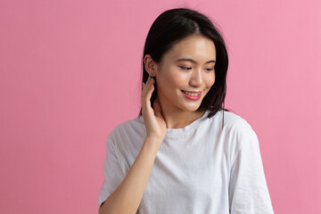 Portrait of asian positive smiling woman on a pink background.