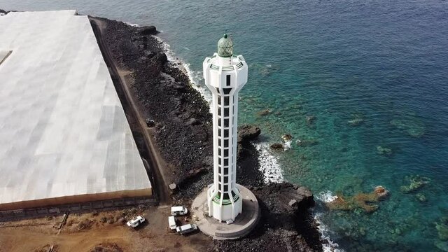 PUERTO NAOS, SPAIN - Aug 15, 2021: Aerial top view of lighthouse, rocks and ocean waves in a volcanic landscape with lava. Punta Lava Lighthouse in La Palma. La Bombilla, Tazacorte
