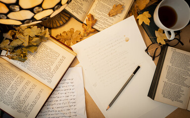 Dark academia aesthetic flat lay desk with Shakespeare sonnets surrounded by fallen autumn leaves, glasses, books, and black tea - obrazy, fototapety, plakaty