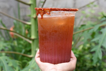 Holding a michelada in the middle of the vegetation