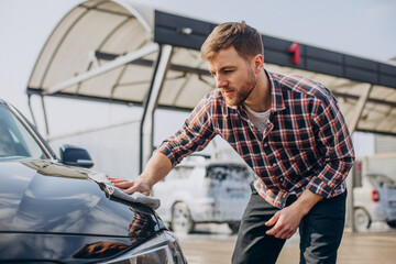 Young man wiping his car after car wash