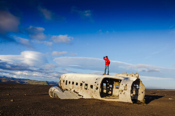 Walking man on the old crashed plane abandoned on Solheimasandur beach near Vik in Iceland