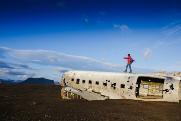 Walking man on the old crashed plane abandoned on Solheimasandur beach near Vik in Iceland