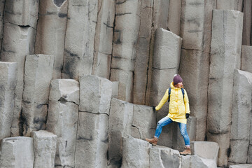 Female traveler walking on rocky formations at Reynisfjara Beach, Vik, Iceland