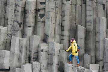Female traveler walking on rocky formations at Reynisfjara Beach, Vik, Iceland