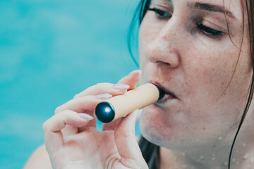 Woman smoking with electronic cigarette. Young woman smoking electronic cigarette in outdoors pool