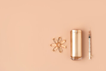 Beautiful composition of gold mockup cosmetic bottle, syringe and vitamin capsules on pastel...