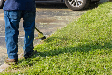 Municipal worker using mower mowing the grass in roadside