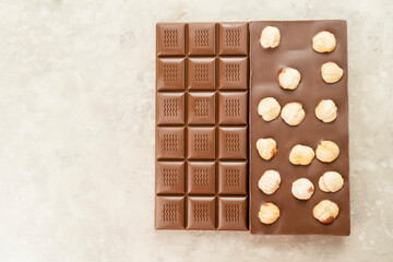 Milk chocolate bar with whole hazelnut kernels on white background. Healthy food concept, delicious chocolate sweets for kids, diet, sugar
